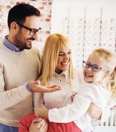 Mother and father smiling at daughter with new glasses