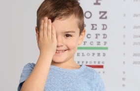 Child with hand over one eye during eye alignment test