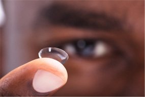Close-up of man holding contact lens in Belmont, MA on his finger