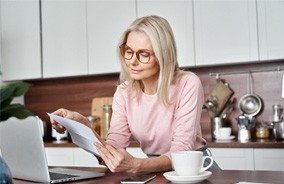 Woman with designer frames in Belmont, MA looking at insurance form
