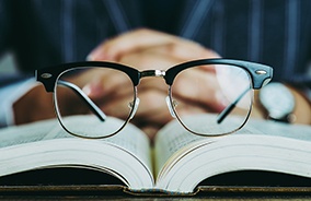 Pair of horn rim glasses resting on an open book
