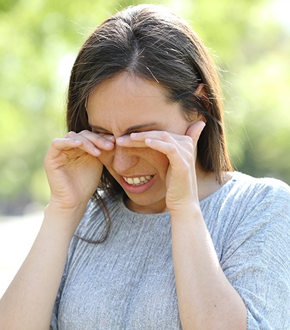 Person with ocular allergies rubbing eyes