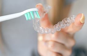 About to brush Invisalign aligner held between fingers