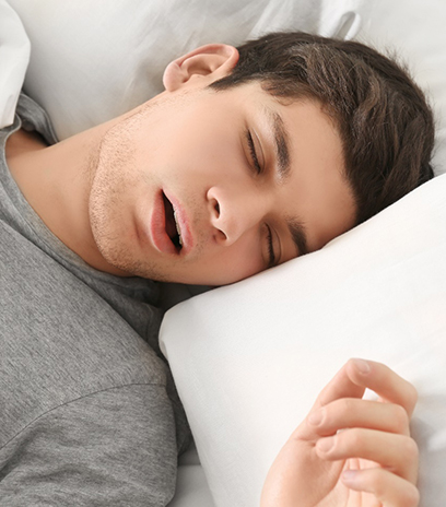 Man in grey shirt sleeping in bed with sleep apnea in Belmont, MA