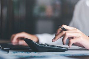 A person holding a pen and using a calculator