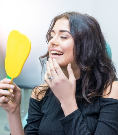 Woman looking in the mirror after her smile makeover