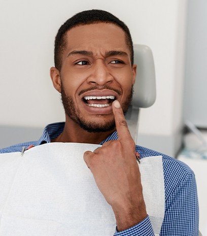 Man in need to dental crown pointing to smile