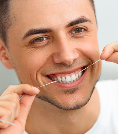Man flossing teeth after dental crown restoration