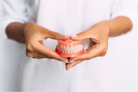 Close-up of hands holding full dentures in Belmont, MA