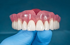 Dentist holding a top set of dentures in Belmont