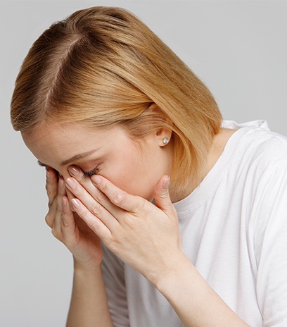 Woman holding face in discomfort before meibomian gland expression