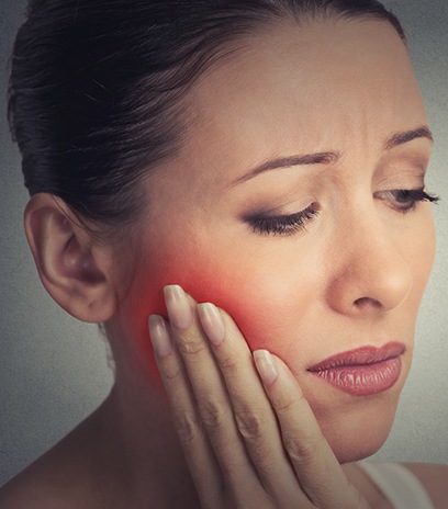 Woman in need of tooth extraction holding jaw in pain