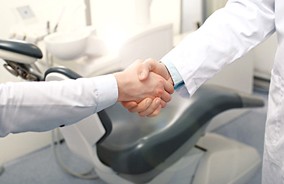 Dentist and patient shaking hands after tooth extraction in Belmont, MA