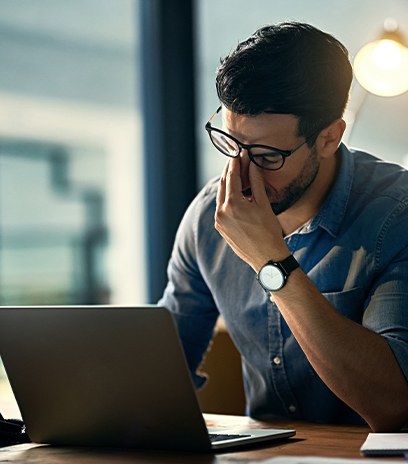 Man with computer fision syndrome holding bridge of nose in pain