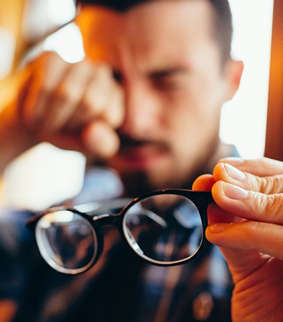 Person with astigmatism rubbing eyes