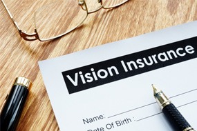 Close-up of a vision insurance form, glasses, and a pen