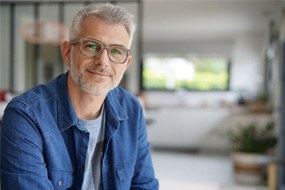 Smiling bearded man with denim jacket and glasses