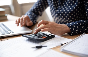 Woman calculating cost of emergency care at desk