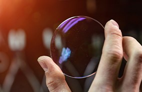 Hand holding up a polycarbonate eyeglass lens