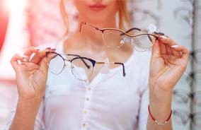 Woman holding two pairs of eyeglasses in Belmont, MA