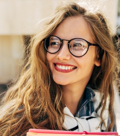 Woman with glasses smiling after visiting optometrist in Belmont, MA