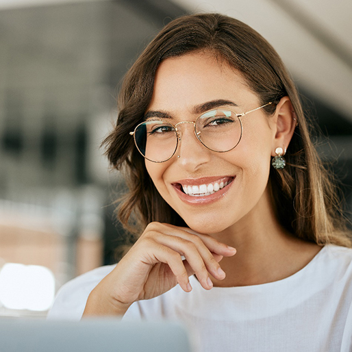 Woman with eyeglasses smiling in white shirt at office