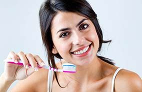 Smiling woman preparing to practice dental implant care in Belmont