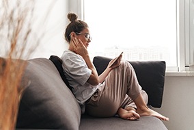 Woman sitting on couch and rubbing jaw