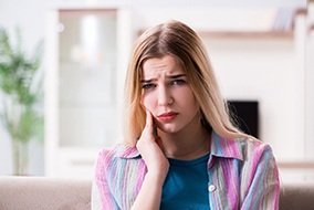 Woman in striped coat rubbing her jaw