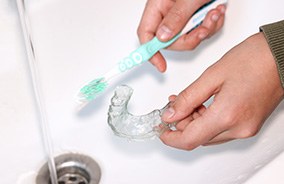 Holding toothbrush and Invisalign aligner in sink