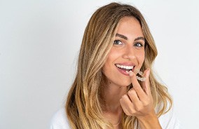 Smiling woman about to put in Invisalign aligner