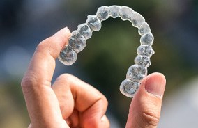 Close-up of hand holding aligner for Invisalign in Belmont, MA