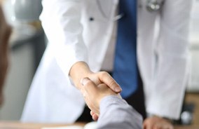 Dentist and patient shaking hands over desk