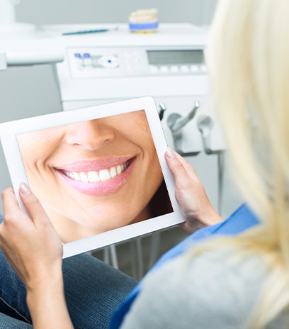 Woman looking at her smile design on tablet computer