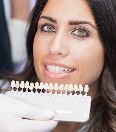 Woman's smile compared with tooth color chart