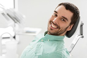 Man in green shirt smiling while sitting in treatment chair