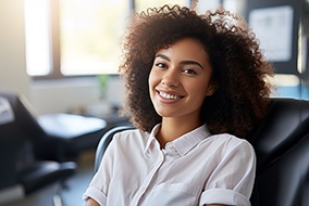 Woman in white shirt smiling while sitting in treatment chair