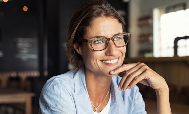 Woman wearing glasses and smiling after treatment during an eye emergency