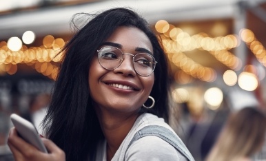 Woman with glasses smiling after eye disease management