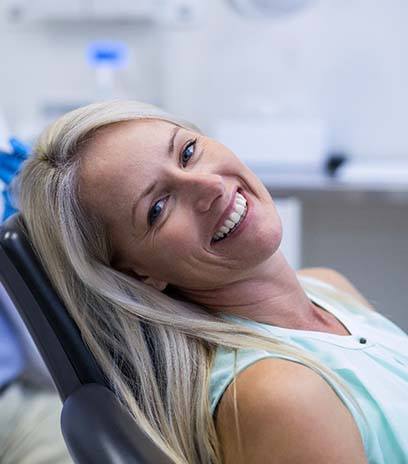 Woman leaning back in her chair visiting emergency dentist in Belmont, MA