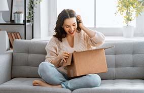 Woman looking inside a box sitting on couch