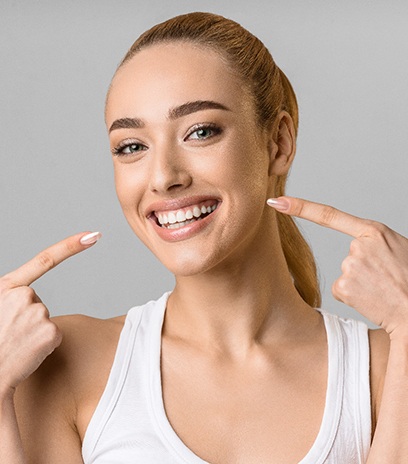 Woman pointing to her smile after veneers