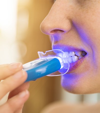 Patient using at home teeth whitening activation light