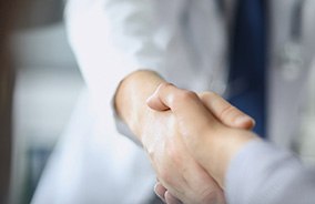 Patient shaking dentist’s hand after teeth whitening in Belmont, MA