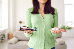 person holding contact lenses and eyeglasses 