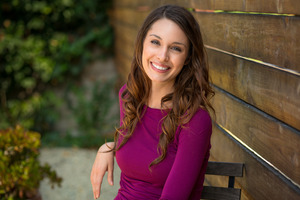 Woman smiling next to a wooden cabin
