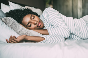 Woman in striped shirt sleeping in bed